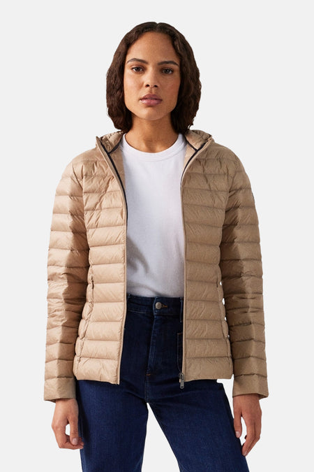 Beige regenjas van JOTT met een capuchon, gedragen met een wit T-shirt en een donkerblauwe jeans.