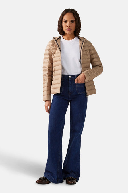 Beige regenjas van JOTT, gedragen met een wit T-shirt en een high-waisted jeans.