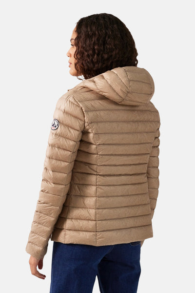 Beige regenjas van JOTT, met capuchon, op een vrouw die een blauwe spijkerbroek draagt.
