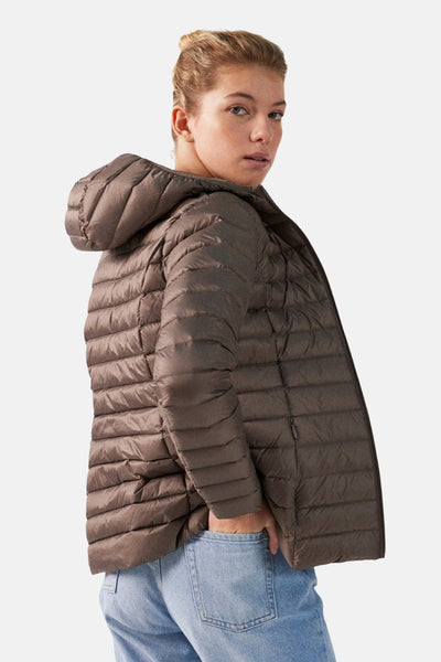 Veste de pluie marron de JOTT, avec capuche et matelassage horizontal, portée avec un jean clair.
