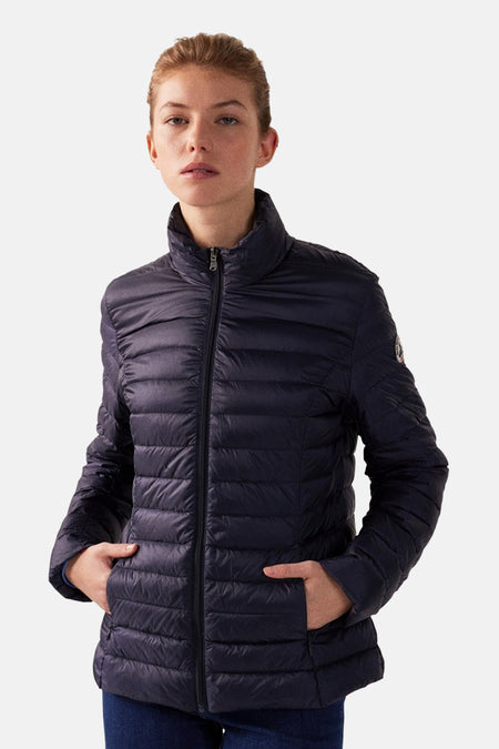 Veste de pluie bleue par JOTT, matelassée avec fermeture éclair et poches, portée par une femme.