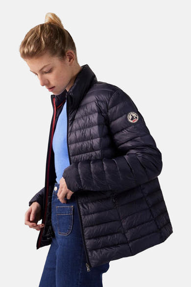 Veste de pluie bleue de JOTT, à rembourrage matelassé, portée avec un pull bleu et un jean.