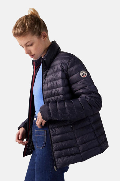 Veste de pluie bleue de JOTT, à rembourrage matelassé, portée avec un pull bleu et un jean.