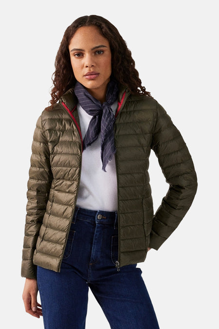 Veste de pluie kaki de JOTT, portée avec un foulard à rayures et un jean bleu.