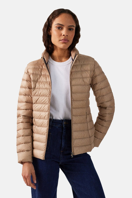 Veste de pluie beige de JOTT, portée avec un t-shirt blanc et un jean foncé.