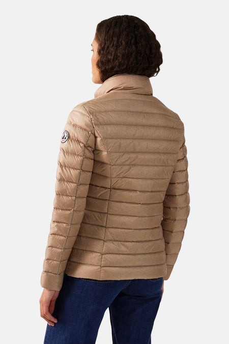 Veste de pluie beige de JOTT, matelassée avec un col montant, portée avec un jean bleu foncé.
