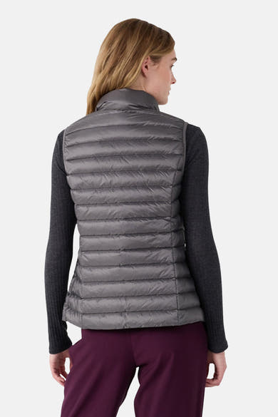 Veste sans manches grise de JOTT, matelassée avec col montant, portée avec un pull gris et un pantalon bordeaux, vue de dos.

