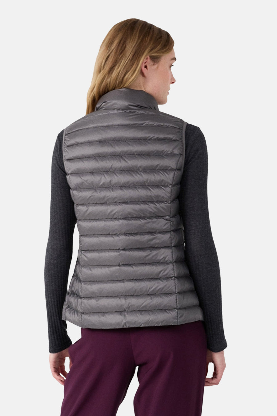 Veste sans manches grise de JOTT, matelassée avec col montant, portée avec un pull gris et un pantalon bordeaux, vue de dos.
