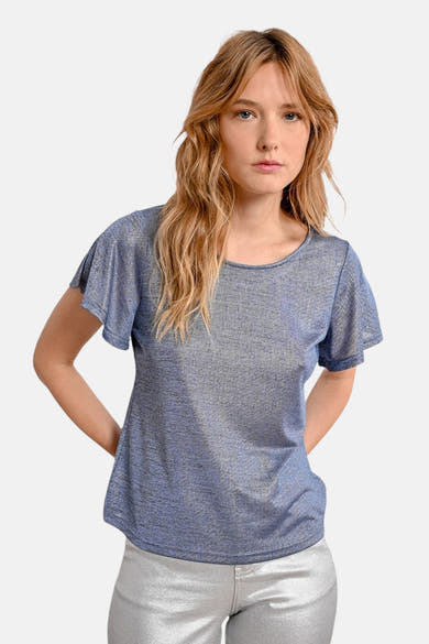 T-shirt bleu à manches courtes de Molly Bracken, avec un aspect brillant porté avec un pantalon argenté.