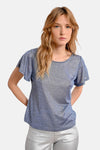 T-shirt bleu à manches courtes de Molly Bracken, avec un aspect brillant porté avec un pantalon argenté.