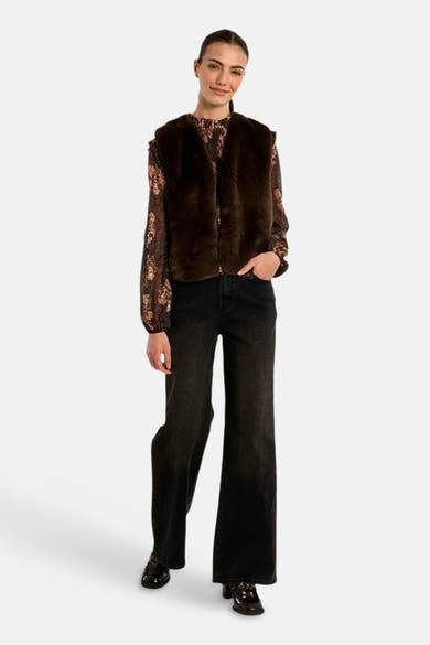 Femme portant un cardigan brun Molly Bracken sur une blouse à motifs et un pantalon noir.
