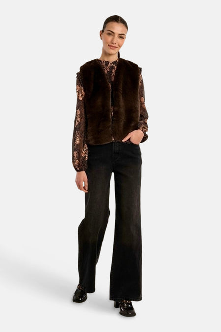 Femme portant un cardigan brun Molly Bracken sur une blouse à motifs et un pantalon noir.