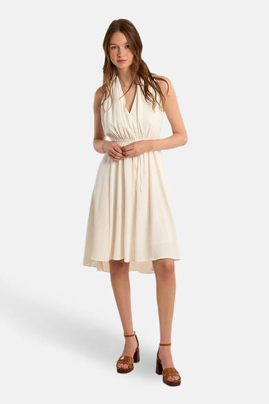 Robe blanche de Molly Bracken avec une coupe évasée, longueur genou, et des sandales marron à talons.
