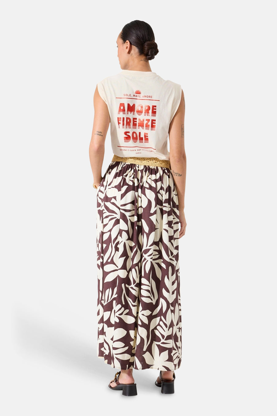 Top écru sans manches de GARCIA, imprimé rouge "Amore Firenze Sole" au dos, porté avec un pantalon ample à motif floral.
