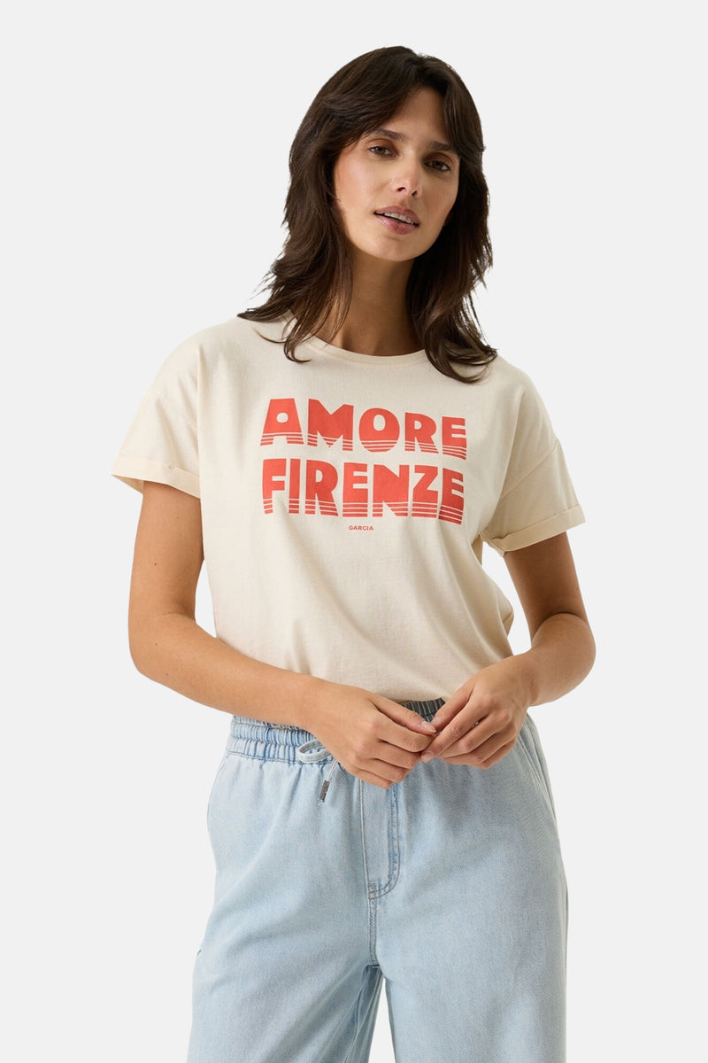 Ecru short-sleeve t-shirt with bold red "AMORE FIRENZE" graphic, worn by model in light denim pants, front view