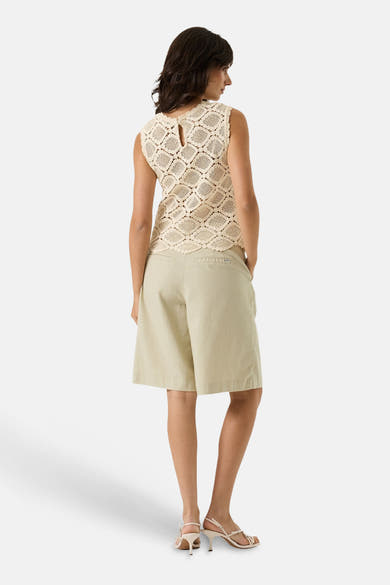 Blouse beige sans manches by GARCIA, en motif ajouré, avec des shorts et des chaussures à talons.