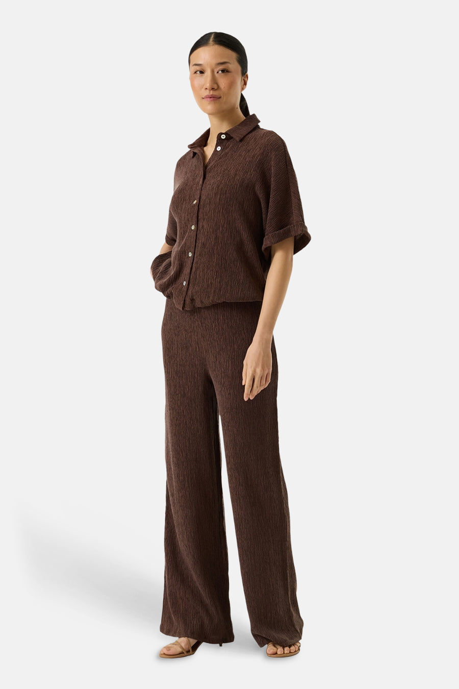 Chemise brun à manches courtes par GARCIA, avec une texture plissée, portée avec un pantalon assorti et des sandales.
