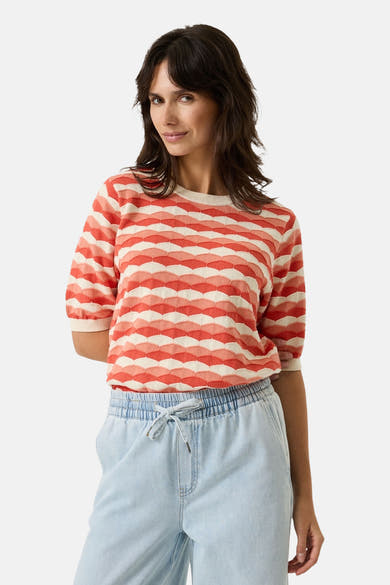 Pull multicolore de GARCIA, à rayures ondulées orange et blanc, porté avec un pantalon décontracté bleu clair.
