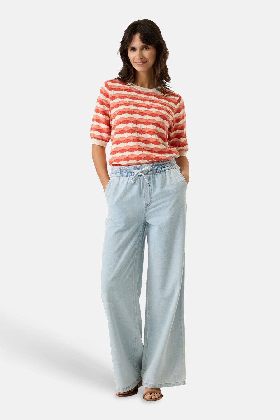 Pull multicolore col rond, de GARCIA, à rayures horizontales ondulées, porté avec un pantalon ample en denim bleu clair.
