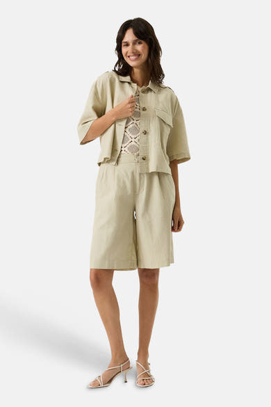 Chemise beige à manches courtes de GARCIA, portée avec un débardeur en dentelle et un bermuda assorti.