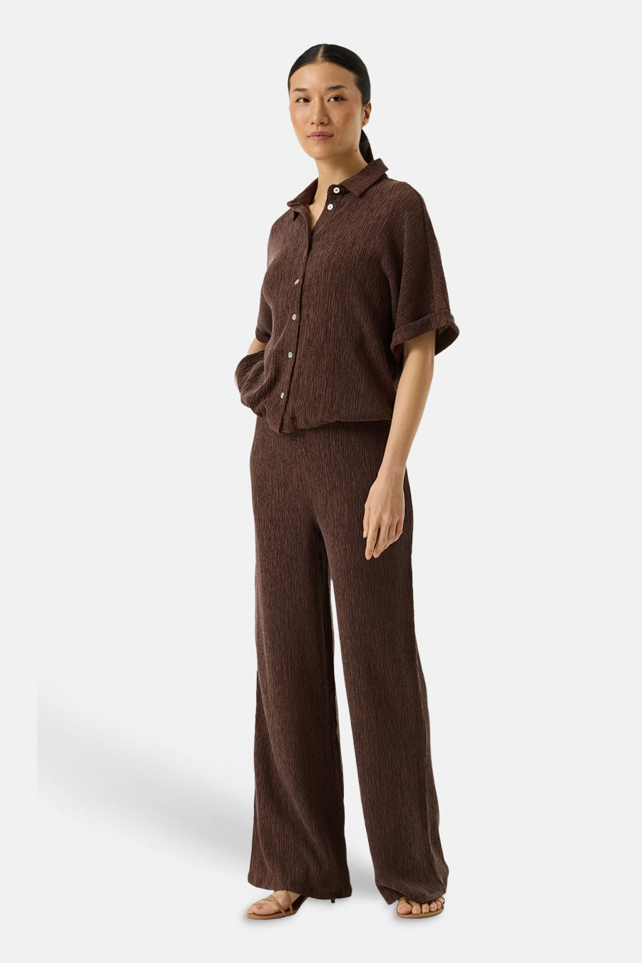 Pantalon brun de GARCIA avec une texture plissée, porté avec un chemisier assorti et des sandales à talons.