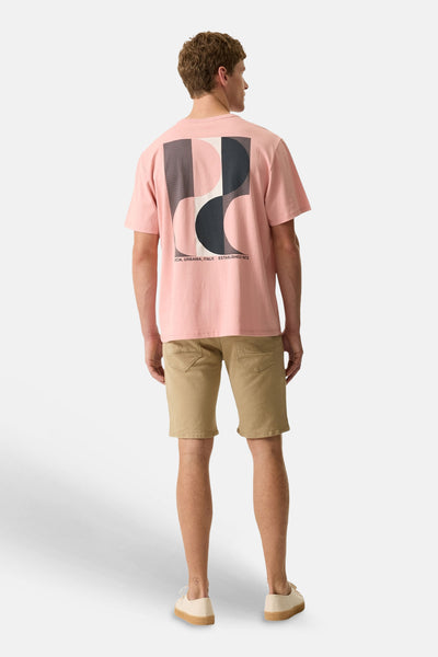 T-shirt rose de la marque GARCIA avec un grand motif géométrique abstrait au dos, porté par un homme avec un short kaki.