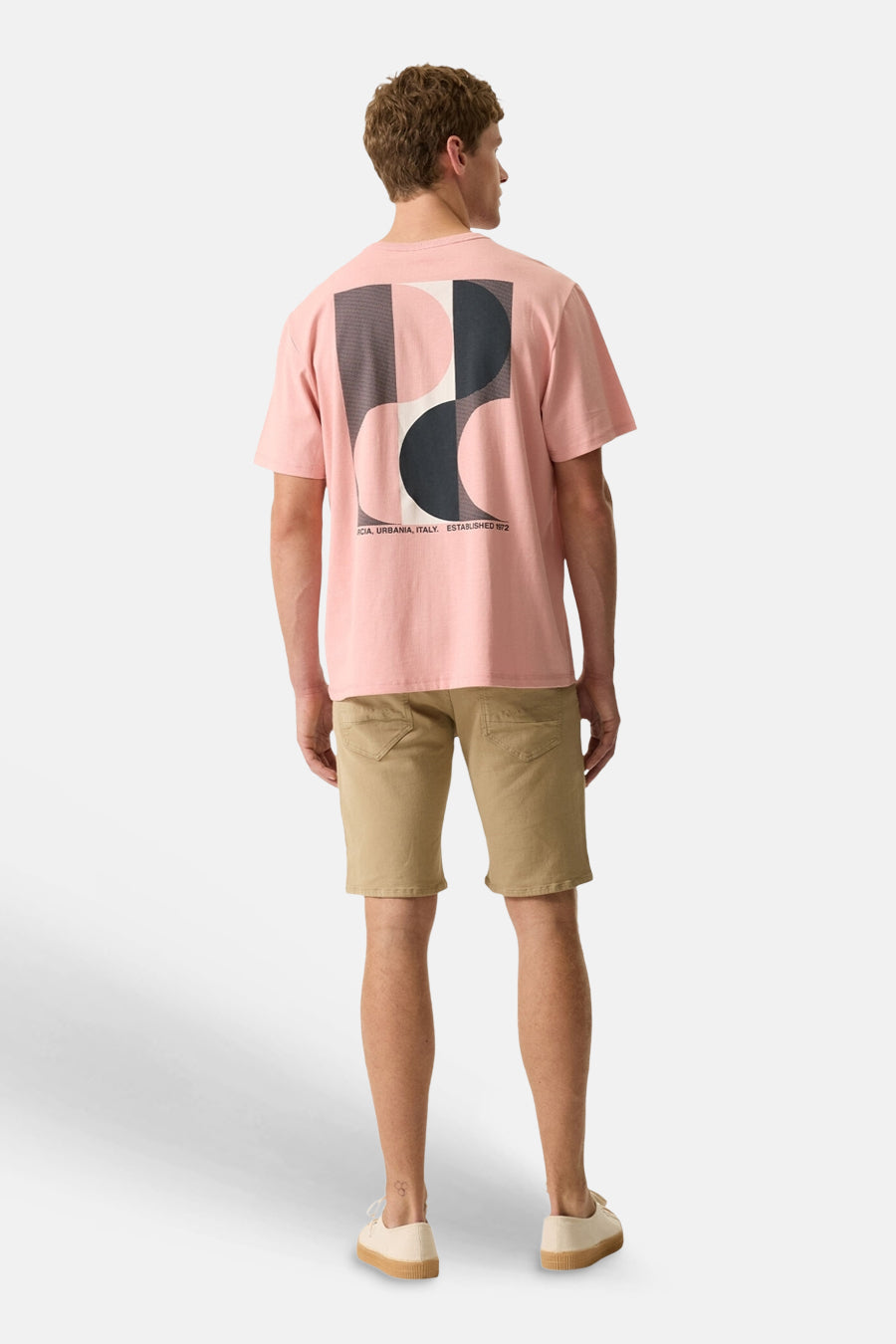 T-shirt rose de la marque GARCIA avec un grand motif géométrique abstrait au dos, porté par un homme avec un short kaki.