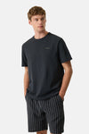 T-shirt noir de GARCIA avec petit logo sur la poitrine, porté par un homme en short rayé.