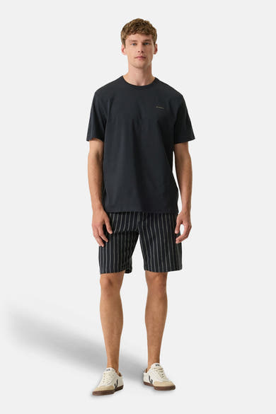 T-shirt noir de GARCIA avec logo discret, porté par un homme avec un short rayé et des baskets.