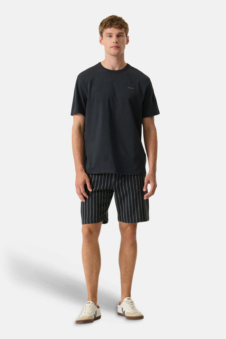Zwart T-shirt van GARCIA met discreet logo, gedragen door een man met een gestreepte korte broek en sneakers.