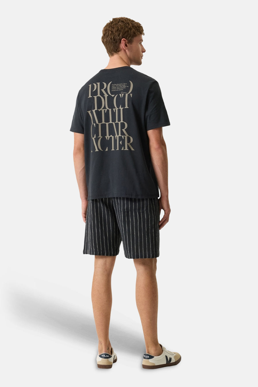 T-shirt noir à manches courtes de GARCIA avec inscription "PRODUCT WITH CHARACTER" au dos, porté avec un short rayé et des baskets claires.