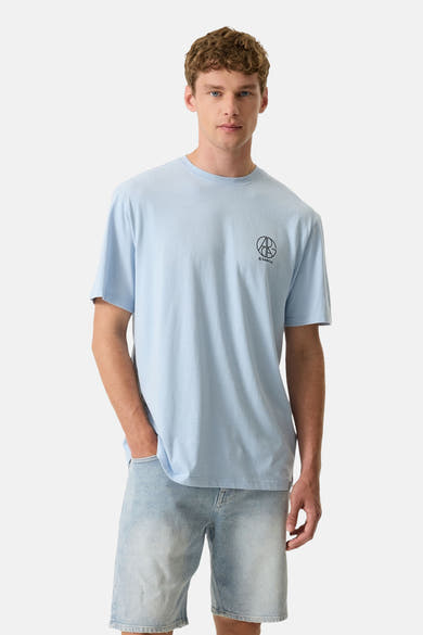 Lichtblauwe T-shirt van GARCIA met een zwart cirkelvormig "AB GARCIA" logo op de borst, gedragen door een man in een lichtblauwe spijkerbroek.