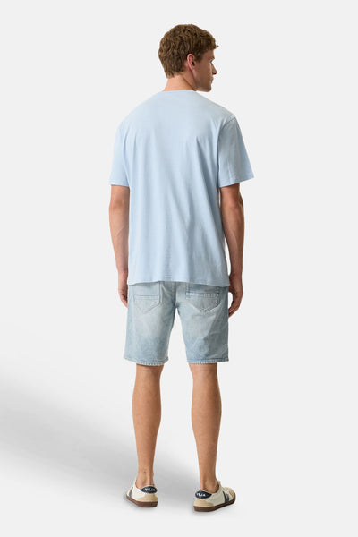Blauw T-shirt van GARCIA, achterkant, gedragen met een lichtblauwe spijkerbroek met korte pijpen en lichte sneakers.