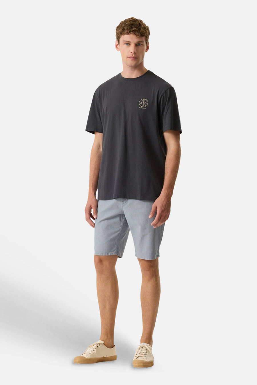 T-shirt gris de GARCIA avec un logo circulaire discret sur la poitrine, porté avec un short bleu clair et des baskets.