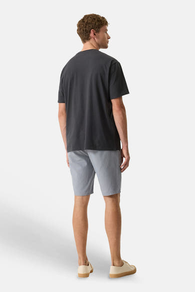 T-shirt gris de GARCIA à manches courtes, porté de dos avec un short gris clair et des chaussures en toile crème.