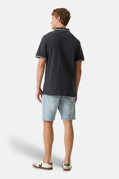 Polo gris foncé avec liserés blancs de GARCIA, vu de dos, porté avec un short en jean et des baskets.