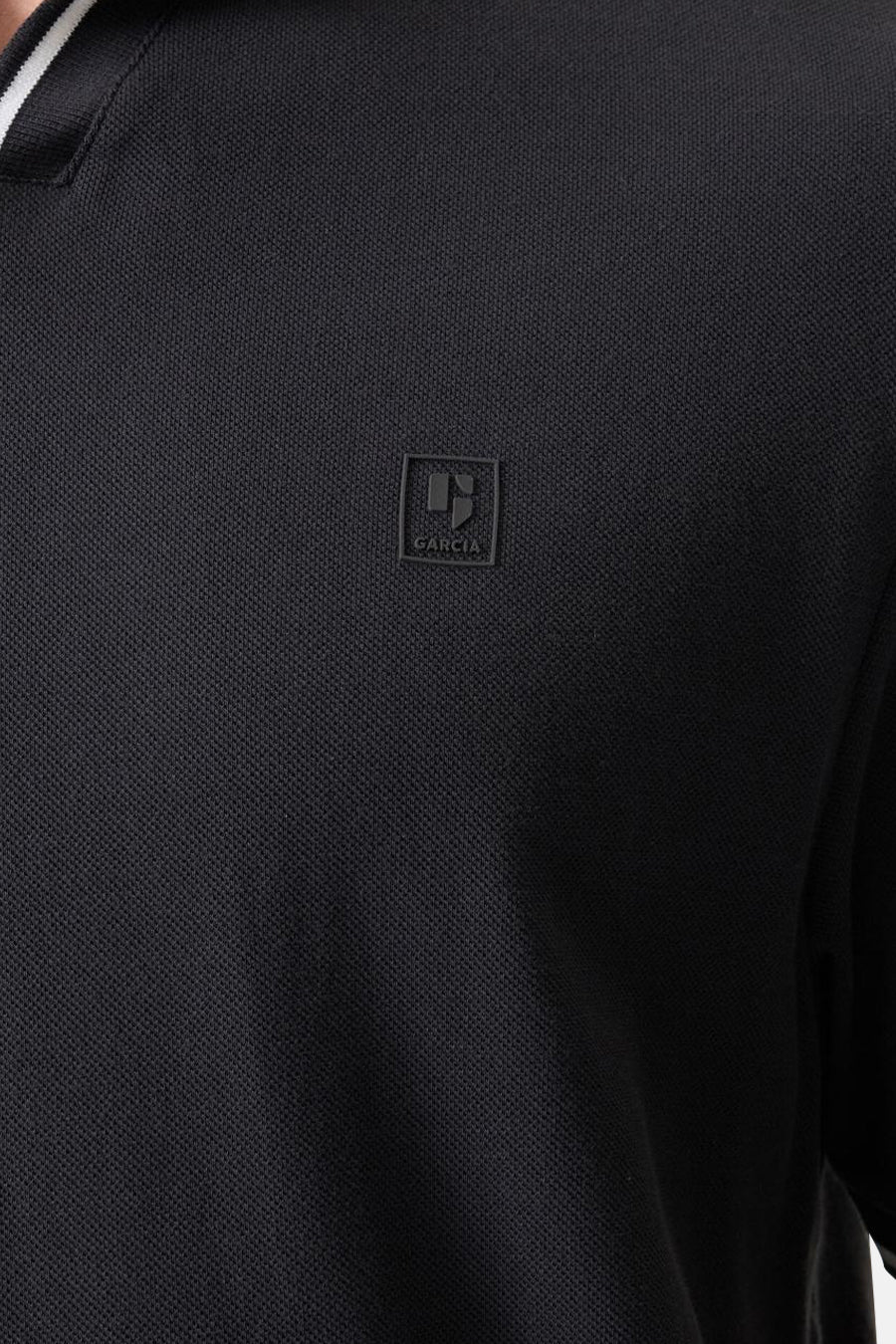 Polo noir de GARCIA avec texture piquée, logo embossé sur la poitrine et col rayé.
