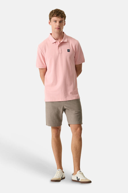 Roze poloshirt van het merk GARCIA met zwart vierkant logo, gedragen door een man in een grijze korte broek en lichte sneakers.