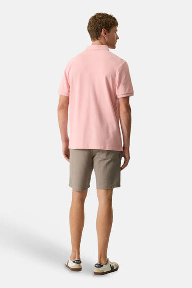 Polo rose de GARCIA, porté de dos par un homme, avec un short marron texturé et des baskets.
