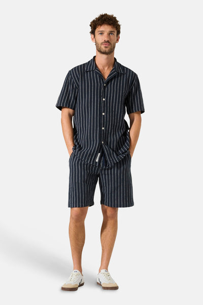 Marineblauwe blouse met fijne witte verticale strepen van GARCIA, met cubaanse kraag en korte mouwen, gedragen met een bijpassende short.