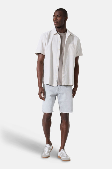 Chemise beige à manches courtes de GARCIA à texture rayée, portée ouverte sur un t-shirt gris avec short en jean clair et baskets.