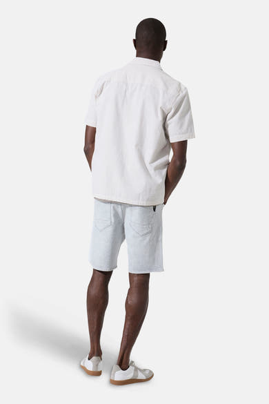 Chemise à manches courtes beige légèrement lignée de GARCIA, vue de dos sur un homme portant un short en jean clair et des baskets.