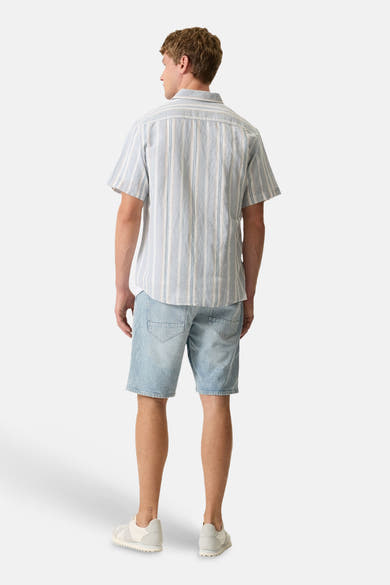 Chemise à manches courtes rayée bleue, blanche et beige de GARCIA, portée de dos avec un short en jean et des baskets.