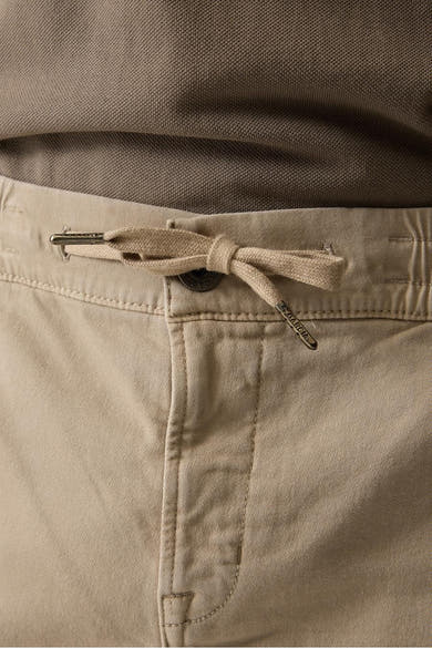 Short beige de GARCIA avec cordon de serrage noué, embouts métalliques gravés et bouton, accompagné d'un polo marron.