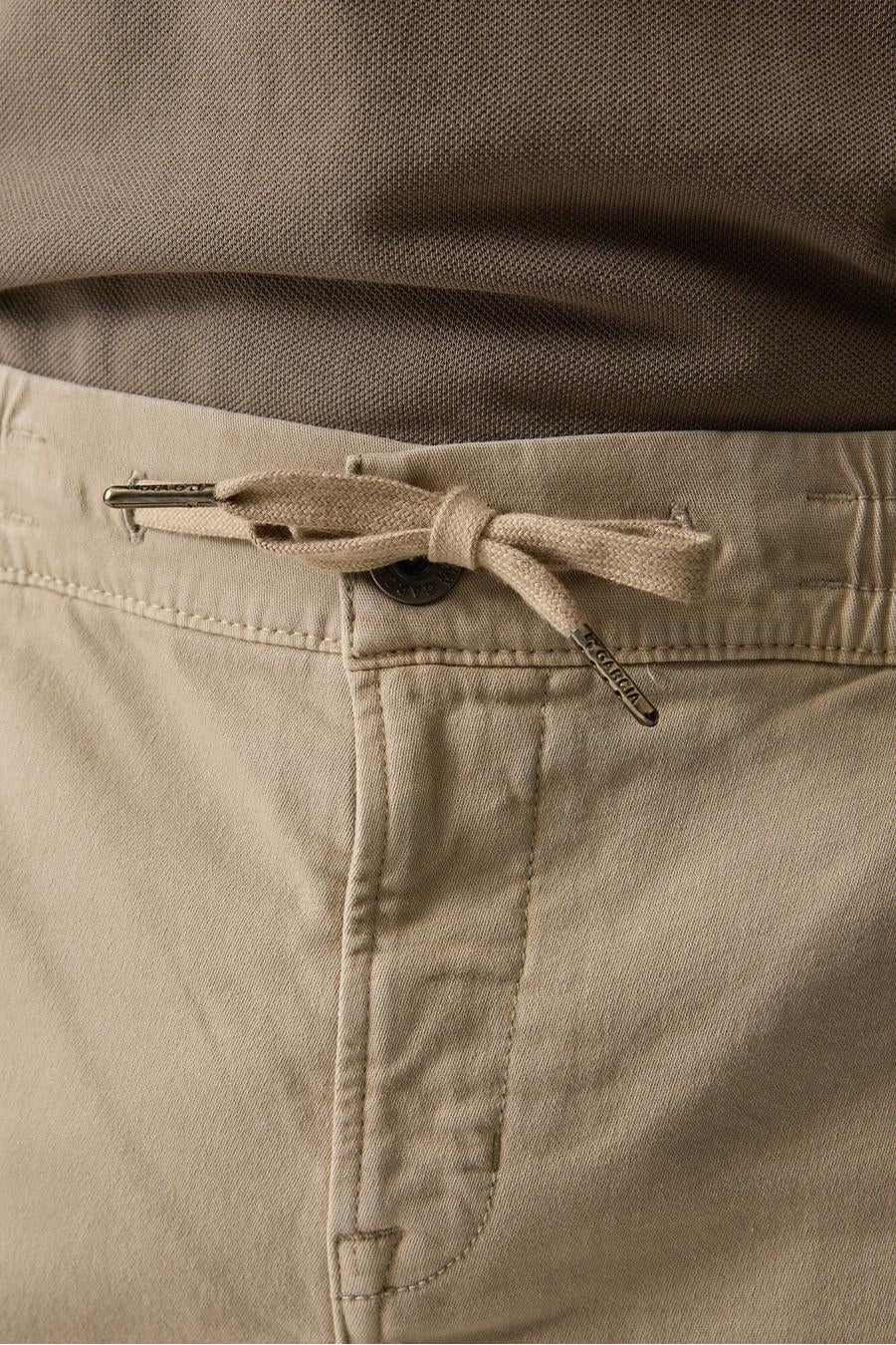 Short beige de GARCIA avec cordon de serrage noué, embouts métalliques gravés et bouton, accompagné d'un polo marron.