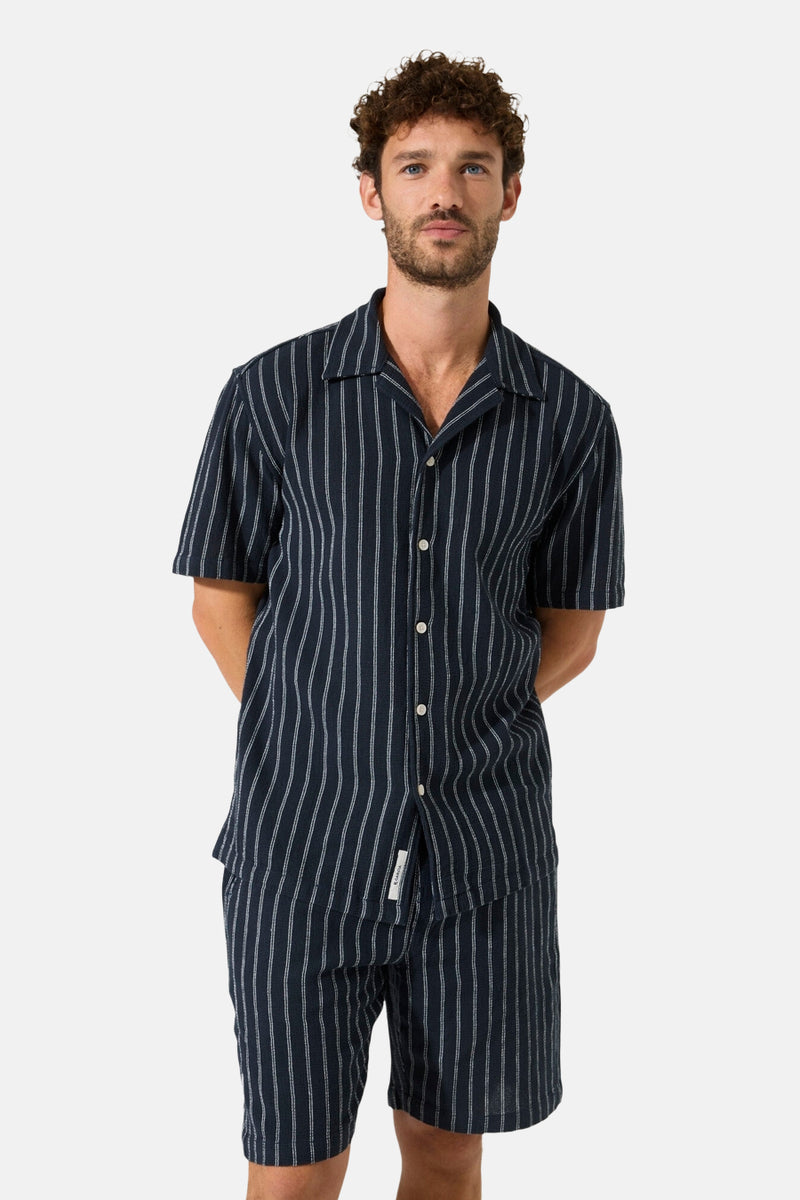 Short bleu de GARCIA à fines rayures verticales blanches, assorti à une chemise.