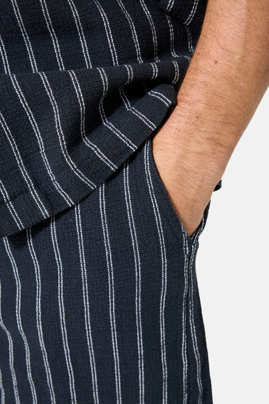 Short bleu de GARCIA à rayures verticales blanches, en tissu texturé, avec une main dans la poche.