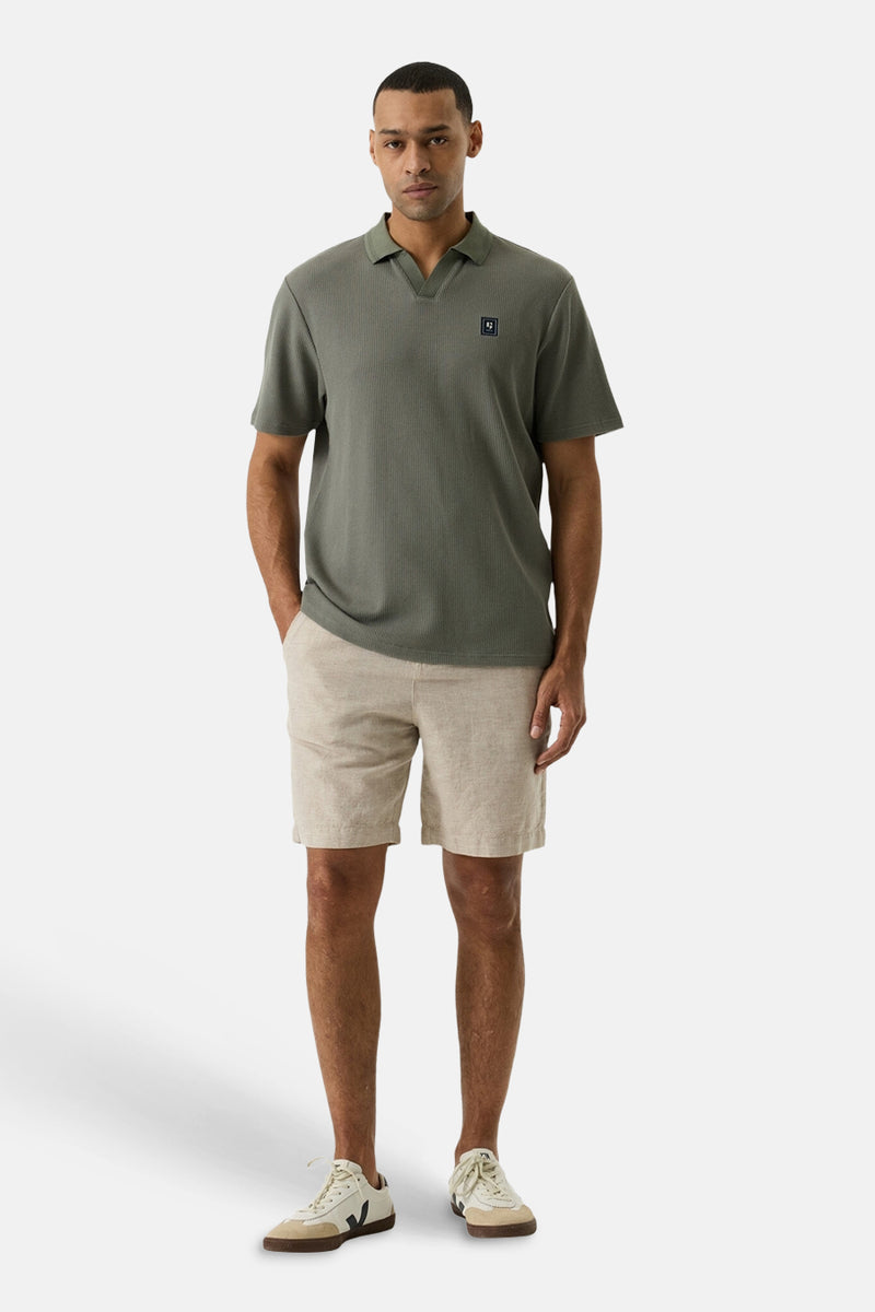 Short beige de GARCIA en tissu léger, porté par un homme avec un polo vert olive et des baskets claires.