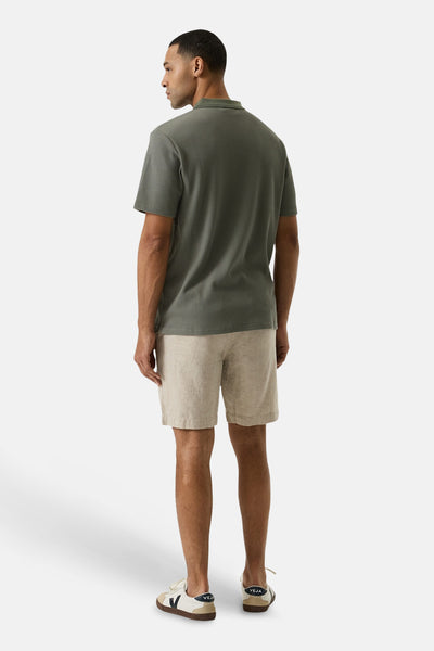 Short beige de GARCIA, en matière texturée, porté de dos avec un polo vert et des baskets.