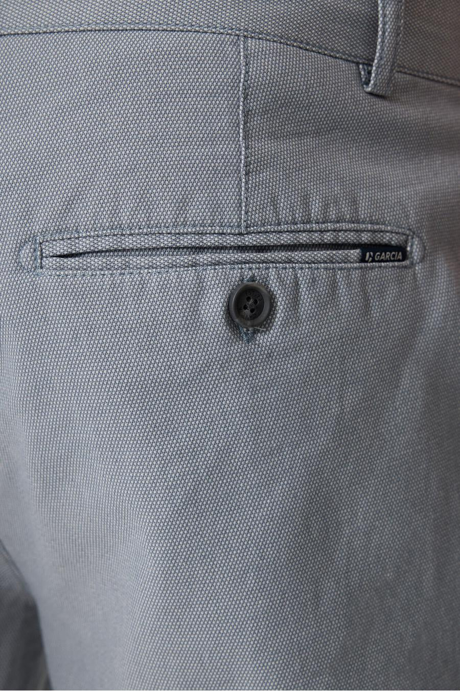 Détail d'un short bleu de GARCIA avec poche arrière boutonnée, étiquette de marque et tissu texturé.